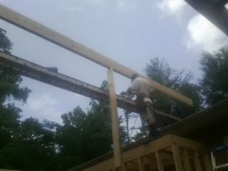 Carpenter setting a ridge beam over a new addition frame — Ice Dam Removal by Roofing Brothers in Farner