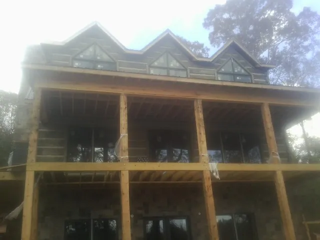 Dormers and porch framing on a large log home under construction — Roof Coating work by our crew in Farner