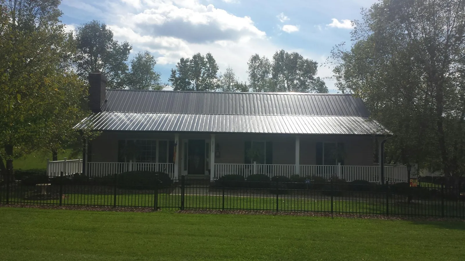 Gray metal roof on a brick ranch with a full width front porch — Gutter Guard Installation work by our crew in Farner