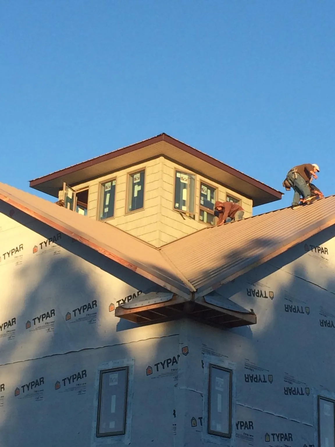 Roofers working around a rooftop cupola on a new metal roof at sunset — Roof Waterproofing in Farner by Roofing Brothers